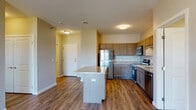 This single-floor unit offers a well-designed, open-concept layout that integrates the kitchen and living areas seamlessly. The kitchen is a standout feature, equipped with stainless steel appliances including a refrigerator, electric range, and built-in microwave. Warm-toned cabinetry with brushed nickel hardware lines the walls, complemented by light granite countertops that extend to a peninsula island, providing additional workspace and casual dining potential. Hardwood-style flooring runs throughout the main living and kitchen areas, adding warmth and continuity.

The living area is bright and open, benefiting from a sliding glass door that leads to a private balcony overlooking a residential neighborhood, allowing for ample natural light. The bedrooms are carpeted for comfort, each featuring windows with blinds that frame outdoor views of the surrounding community.

The bathroom includes a tub-shower combination, a wood-toned vanity, and tile flooring in a natural stone pattern. A second bathroom features a granite-topped vanity with an undermount sink and a large mirror. The overall palette of neutral tones, quality finishes, and functional layout creates a clean, contemporary living environment.