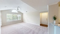 This 2-bedroom, 1-bathroom home delivers a thoughtfully organized single-floor layout designed for comfortable living. The living room is a standout space, featuring dramatic vaulted ceilings, a ceiling fan, and a striking arched window above a large picture window that floods the room with natural light and offers views of lush greenery outside. Soft carpeting and neutral-toned walls create a warm, inviting atmosphere throughout. The kitchen is well-appointed with white shaker-style cabinetry, granite countertops, a subway tile backsplash, stainless steel appliances including a refrigerator and dishwasher, and a breakfast bar peninsula that opens to the living and dining areas. Hardwood-style flooring anchors the kitchen and entry. The primary bedroom is generously sized, complete with a ceiling fan, carpeted flooring, and a walk-in closet outfitted with wire shelving for organized storage. The second bedroom also features a ceiling fan and a window with outdoor views. The shared bathroom includes a granite-topped vanity with white cabinetry, a large mirror, and a shower/tub combination. A dedicated in-unit laundry area with a washer and overhead shelving adds everyday convenience, rounding out this functional and comfortable home.