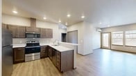 Located at 3027 E Upriver Drive in Spokane, Washington, this two-bedroom, one-bathroom unit offers a well-designed single-floor layout with modern finishes throughout. The open-concept kitchen and living area serves as the heart of the space, featuring rich dark wood cabinetry, white quartz countertops, a peninsula with undermount sink, and a full suite of stainless steel appliances including a range, microwave, refrigerator, and dishwasher. Light wood-tone luxury vinyl plank flooring runs throughout, creating a clean and cohesive aesthetic. The living room is bright and airy, benefiting from a wall of windows and a glass door that invite abundant natural light and views of the surrounding landscape. A wall-mounted mini-split unit provides efficient climate control. The generously sized primary bedroom features a bank of large windows offering panoramic outdoor views, while the second bedroom includes a sliding closet door and its own window. A dedicated walk-in closet provides ample storage. The full bathroom is well-appointed with a single-sink vanity, wood-toned cabinetry, a large mirror, and a shower-tub combination. Recessed lighting throughout adds a polished, contemporary feel to this thoughtfully designed Spokane residence.