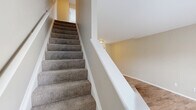 Located at 4045 Langston Pl in Sylvania, Ohio, this two-story home offers a practical and well-organized layout across two floors. The main level features an open-concept living room and kitchen area bathed in natural light from a large front-facing window. The living room is anchored by a classic fireplace with a white mantle and is finished with warm hardwood-style flooring. A clever built-in shelving nook tucked beneath the staircase adds functional storage to the space.

The kitchen is outfitted with rich, dark wood cabinetry on both upper and lower levels, white countertops, a stainless steel sink, and white appliances including an electric range and over-the-range microwave. Light wood-style flooring and a window bringing in natural light complete the kitchen's clean, functional aesthetic.

Upstairs, two carpeted bedrooms provide comfortable retreats, each featuring neutral tones and windows overlooking the surrounding neighborhood. The spacious primary bedroom includes a closet and ample room for furnishings. A full shared bathroom on the upper level features a double-sink vanity with dark cabinetry, white countertops, a tub-shower combination, and wood-style flooring, offering both comfort and practicality.