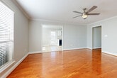 This single-story home offers three bedrooms and two bathrooms across a thoughtfully designed floor plan. The main living area makes a strong first impression with gleaming hardwood floors, crown molding, a textured ceiling, and a ceiling fan with light fixture. Multiple windows dressed with blinds allow natural light to fill the space.

The kitchen is outfitted with white cabinetry, granite-style countertops, and black appliances including a range, over-the-range microwave, and refrigerator. Light tile flooring runs through the kitchen and extends into a bright dining area, which features a large window overlooking greenery outside.

The bedrooms are carpeted and each include ceiling fans and windows with blinds. One bedroom features a closet and connects conveniently to the rest of the home via hardwood-floored hallways. A dedicated laundry room includes tile flooring, overhead shelving, and washer/dryer hookups.

The bathrooms are finished with tile flooring, white vanities with granite-style countertops, and tub/shower combinations. Neutral gray tones throughout the home create a clean, cohesive aesthetic well-suited for a variety of furnishing styles.