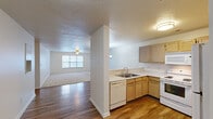 Located at 2000 Trellis Pointe Dr in Holly Springs, NC, this single-floor, three-bedroom, two-bathroom residence offers a practical and comfortable layout across a generous footprint. The open-concept kitchen and living area form the heart of the home, featuring warm wood-toned cabinetry, a U-shaped kitchen layout with white appliances including a range, dishwasher, microwave, and refrigerator, and light-toned countertops with a breakfast bar. A seamless transition to the living room is enhanced by durable hardwood-style flooring, a ceiling fan, and natural light from front-facing windows. The three bedrooms are finished with plush wall-to-wall carpeting, ceiling fans, and windows with blinds that invite natural light. The spacious primary bedroom includes a dedicated walk-in closet outfitted with wire shelving for organized storage. Additional bedrooms feature standard closets with built-in rods. Both bathrooms are well-appointed, with the primary bath offering a wide vanity, dual sinks, and large mirrors. Throughout the home, a neutral color palette, textured ceilings, and clean white trim create a bright, move-in-ready atmosphere suited for everyday living.