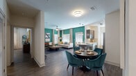 This single-floor residence makes a striking first impression with its bold teal accent walls and an open-concept layout connecting the living, dining, and kitchen areas. The living room features a ceiling fan, ample natural light from large windows dressed with sheer curtains, and generous space for comfortable seating arrangements. The adjacent dining area accommodates a round table with upholstered chairs, positioned near a stainless steel refrigerator and a built-in wine rack, adding a refined touch.

The galley-style kitchen is well-appointed with dark espresso cabinetry, quartz countertops, a tile backsplash, and a full suite of stainless steel appliances, including a dishwasher, range, microwave, and refrigerator. A window above the counter brings in natural light.

Two bedrooms each feature distinctive accent walls—one showcasing a dramatic watercolor-style mural and another with a geometric metallic pattern—along with ceiling fans, large windows, and wood-style flooring. The bathroom offers a dual-sink vanity with dark cabinetry and modern light fixtures. Additional conveniences include an in-unit laundry area with a full-size washer and dryer, and well-organized closet space with wire shelving throughout.