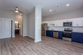 Located at 695 Meeting St in Charleston's historic 29403 zip code, this single-floor residence offers a thoughtfully designed interior that blends modern finishes with functional living spaces. Warm hardwood-style flooring runs continuously throughout, creating a cohesive and inviting atmosphere from entry to living area.

The kitchen is a standout feature, showcasing a striking two-tone cabinetry design with bold navy lower cabinets and crisp white upper cabinets, complemented by light countertops and a subway tile backsplash. A full suite of stainless steel appliances — including a range, over-the-range microwave, dishwasher, and refrigerator — ensures a well-equipped culinary space.

The open living area is bright and airy, with recessed lighting, a ceiling fan, and structural columns that add architectural character. A large bank of windows invites generous natural light, enhancing the spacious feel of the room. An in-unit washer and dryer area is conveniently accessible from the living space.

The bathroom is clean and functional, featuring a full soaking tub with a subway-tiled surround, chrome fixtures, and a navy vanity with a round mirror, consistent with the home's modern aesthetic. Louvered closet doors, recessed lighting in the entry corridor, and neutral warm-gray walls throughout complete the polished, move-in-ready presentation of this Charleston residence.