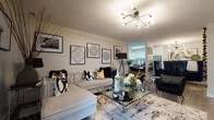 Located at 1004 Des Plaines Ave in Forest Park, Illinois, this thoughtfully designed single-floor residence offers a cohesive blend of contemporary style and functional living. The open-concept living and dining area is anchored by light hardwood flooring, a sculptural multi-arm chandelier, and a curated gallery wall of framed artwork. A tufted sectional sofa, mirrored glass coffee table, and bold accent chairs create a sophisticated yet comfortable atmosphere that flows seamlessly into the kitchen and dining space.

The kitchen is outfitted with two-tone cabinetry — crisp white uppers paired with slate gray lowers — topped with light quartz countertops and accented by a classic white subway tile backsplash. Stainless steel appliances, a matte black faucet, and an in-unit washer complete this highly functional space.

The primary bedroom is a dramatic retreat featuring a chrome four-poster bed frame, a deep royal blue tufted headboard, a crystal pendant light, and mirrored nightstands and dresser. A second bedroom offers a more relaxed aesthetic with a tan tufted headboard, soft blue accents, and natural light from a window with plantation shutters.

Both bathrooms are clean and modern, featuring gray vanities, LED-backlit mirrors, and wood-look flooring, providing a polished finish throughout the home.