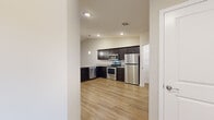 Located at 11450 Willow Pond Dr. in Louisville, KY, this single-floor, 2-bedroom, 2-bathroom home offers a thoughtfully designed layout with modern finishes throughout. The open-concept kitchen and living area serves as the heart of the home, showcasing rich dark cabinetry, granite-style countertops, a full suite of stainless steel appliances—including a refrigerator, range, microwave, and dishwasher—and warm wood-look flooring. Pendant lighting and recessed fixtures illuminate the space, while vaulted ceilings add a sense of openness. A walk-in pantry with built-in shelving provides generous storage directly off the kitchen. The living area features wood-look flooring, a ceiling fan, and sliding doors with vertical blinds that invite natural light. Both bedrooms are carpeted and offer ceiling fans, natural light from windows with blinds, and easy access to closets. The spacious primary bedroom connects to a well-finished bathroom featuring a dark vanity with granite-style countertops, a large mirror, and polished nickel fixtures. The second bathroom mirrors this style with a tub-shower combination and wood-look flooring. Two dedicated closets round out the storage throughout. Neutral warm tones across walls and finishes create a cohesive, move-in-ready atmosphere.