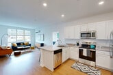 Located at 223 Garden St in South Burlington, Vermont, this well-appointed 3-bedroom, 2-bathroom single-floor residence offers a clean, contemporary design with a functional and open layout. The heart of the home is a combined kitchen, dining, and living area that flows seamlessly together, creating a spacious and inviting atmosphere. The kitchen is outfitted with crisp white shaker cabinets, stainless steel appliances including a dishwasher, microwave, and range, and a peninsula with bar seating — ideal for casual dining or entertaining. Warm, hardwood-style flooring extends throughout the entire unit, tying the spaces together cohesively. The living area benefits from natural light through large windows and includes a wall-mounted mini-split system for year-round climate control. Three well-proportioned bedrooms offer ample closet storage, with six closets distributed across the unit. The primary bedroom is generously sized. Both bathrooms feature white vanities, full-size tubs with shower curtains, and modern fixtures. A dedicated laundry room and a hallway connecting the private spaces add to the practical layout. Recessed lighting throughout keeps the interiors bright and modern, complementing the unit's clean, neutral color palette.