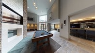 This expansive amenity lounge is designed to impress, combining contemporary architecture with thoughtfully curated entertainment and social spaces. Soaring double-height ceilings flood the main area with natural light through floor-to-ceiling glass doors that open to an outdoor patio beyond. A dramatic stacked-stone accent wall anchors the lounge seating area, which features an inset fireplace and a wall-mounted television, surrounded by plush cream armchairs and rich dark wood furnishings that create an inviting atmosphere.

The games area is a standout highlight, housing a classic billiards table on stone-look tile flooring alongside a shuffleboard table set against a bold teal accent wall with its own dedicated seating nook and mounted display screen. Pendant globe lighting and wall sconces add warm, layered illumination throughout.

A sophisticated full-service bar area offers bar-height seating along a sleek counter, pendant lighting above a stone-tile backsplash, and an integrated television — ideal for social gatherings. A compact wet bar with a draft tap and a cozy banquette booth with a marble-top table provide additional intimate entertaining options. Neutral stone-look tile flooring, curated artwork, and a consistent palette of warm grays, browns, and teal accents tie all zones together into a cohesive, upscale communal retreat.
