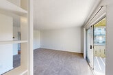 Located at 3815 Susan Drive in San Bruno, California, this one-bedroom, one-bathroom residence offers a practical and well-organized single-floor layout. The living area is carpeted throughout and features a textured ceiling, built-in open shelving, and a sliding glass door that welcomes natural light and provides access to the outdoors. The galley-style kitchen is efficiently designed with white cabinetry, dark laminate countertops, hardwood-style flooring, an electric range, and a refrigerator — providing all essential cooking amenities in a compact, functional space. The bedroom is generously proportioned with soft carpet flooring, a window overlooking the surrounding neighborhood, and direct access to a dedicated closet complete with built-in shelving for organized storage. A second door from the bedroom leads conveniently to the full bathroom, which features a clean white tub and shower combination. Throughout the residence, the neutral white walls and light tones create a bright and cohesive ambiance. The straightforward layout maximizes the use of available space, making this home a functional and comfortable option in the San Bruno area.