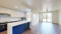 This well-appointed single-floor residence offers four bedrooms and two bathrooms within a thoughtfully designed layout. The open-concept kitchen and living area serves as the heart of the home, featuring striking navy blue cabinetry paired with crisp white countertops and upper cabinets. Stainless steel appliances, including a refrigerator and range, complement the modern aesthetic, while a central island provides additional workspace and casual dining. Rich hardwood-style flooring runs throughout the main living areas, adding warmth and continuity to the space.

The living room is bright and airy, bathed in natural light from large windows and a sliding glass door that opens to a private balcony, offering pleasant outdoor views. A ceiling fan adds comfort to this inviting gathering space.

The four bedrooms are carpeted for comfort and each feature windows that bring in natural light. Closets with sliding doors provide practical storage. The bathrooms are finished with coordinating blue cabinetry and white countertops; one bathroom includes an accessible tub and shower combination equipped with grab bars. A dedicated utility closet houses the water heater, keeping all essentials neatly contained. The overall design balances modern style with functional, everyday livability.