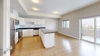 Located at 208 Woolwich St S in Breslau, Ontario, this well-appointed one-bedroom, one-bathroom unit offers a thoughtfully designed layout with modern finishes throughout. Light oak laminate flooring runs continuously across all rooms, complementing the neutral grey walls and crisp white trim.

The open-concept kitchen and living/dining area forms the heart of the unit. The kitchen is outfitted with white shaker-style cabinetry, dark granite countertops, a subway tile backsplash, and a full suite of stainless steel appliances including a refrigerator, stove, and built-in microwave. A central island with matching dark granite provides additional prep space and casual seating. The adjoining living and dining area is bright, with a window offering outdoor views and access to a private balcony.

The bedroom is a comfortable size, featuring a large double-door closet with panelled doors, a window with a roller blind, and a tray ceiling detail that adds architectural interest. A hallway connecting the main living area to the bedroom also provides access to two closets and the in-suite laundry.

The bathroom features a soaker tub and shower combo with full white subway tile surround and chrome fixtures, paired with light flooring for a clean, contemporary finish. The entrance provides a practical transition into the unit, completing a functional and modern floor plan.