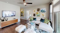 This well-appointed 2-bedroom, 2-bathroom residence is laid out on a single floor, offering a cohesive and functional flow throughout. The open-concept kitchen is a standout feature, showcasing rich dark cabinetry, white quartz countertops, a textured tile backsplash, and a full suite of stainless steel appliances. A large center island with a built-in sink and seating for multiple guests makes it ideal for both cooking and casual dining. Adjacent to the kitchen, the dining area is bathed in natural light from oversized windows dressed with layered drapes, creating an elegant setting. The living room features durable hardwood-style flooring, a ceiling fan, and direct access to a private balcony through sliding glass doors, extending the living space outdoors. Both bedrooms are carpeted for comfort and include ceiling fans, generous walk-in closets with built-in shelving and hanging rods, and ample natural light. The primary bathroom offers a glass-enclosed shower and a well-sized vanity with dark cabinetry and quartz countertops, while the second bathroom features a soaking tub-shower combination and a large framed mirror. Neutral tones and consistent finishes lend a cohesive, modern aesthetic throughout the entire residence.