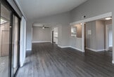 This single-story residence at Via La Paloma in Riverside, California offers a thoughtfully designed layout with a variety of finishes and architectural details. The open living area immediately draws attention with its vaulted ceilings, which lend a sense of spaciousness and volume to the room. Wood-look plank flooring flows throughout the main living spaces, complemented by neutral wall tones and a textured ceiling. A ceiling fan serves the living area, while a sliding glass door with vertical blinds opens to an outdoor view of surrounding greenery, alongside an additional window that brings in ample natural light.

The kitchen features white cabinetry, stone-look countertops, a peninsula with bar seating potential, and white appliances including a refrigerator and gas range. A skylight adds brightness to this functional space.

The bedrooms are carpeted for comfort, each with windows that frame outdoor views. One bedroom benefits from vaulted ceilings and wood-look flooring, adding a distinct character. A primary bedroom includes direct access to an en-suite bathroom with a long vanity, stone-look countertops, and a walk-in closet. An additional full bathroom features a tub-shower combination and matching finishes, maintaining a consistent, clean aesthetic throughout the home.