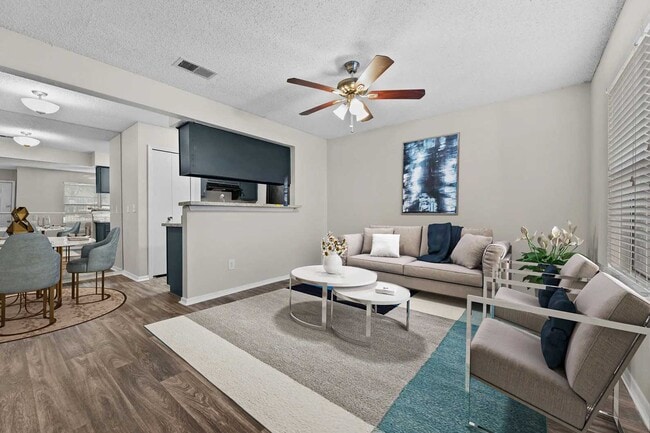 Living room with beige sofa, white coffee table, ceiling fan, framed wall art, and open view to dining area and kitchen - Walnut Creek
