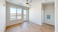 Located at 1803 S 46th St in Rogers, Arkansas, this well-appointed 2-bedroom, 2-bathroom unit offers a thoughtfully designed single-floor layout with a clean, contemporary aesthetic throughout. The open-concept kitchen and living area serves as the heart of the home, featuring a central island with a sink, crisp white quartz countertops, two-tone cabinetry in white and gray, subway tile backsplash, and a full suite of stainless steel appliances including a side-by-side refrigerator, range, and built-in microwave. Light hardwood-style flooring runs throughout the main living areas, complemented by recessed lighting. The primary bedroom offers balcony access through a glass door, large windows framing open views of the surrounding Rogers cityscape, a ceiling fan, and a walk-in closet with wire shelving. The second bedroom is carpeted and equally bright, with a large window and ceiling fan. Both bathrooms are finished with white subway tile — one featuring a glass-enclosed walk-in shower, the other a full soaking tub and shower combo — each paired with modern gray vanities and light wood flooring. The unit's elevated position allows for expansive outdoor views from multiple rooms, enhancing the overall sense of openness and natural light.