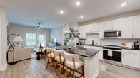 Located at 713 Adelynn Ln in Greensboro, NC, this well-designed single-floor home offers 2 bedrooms and 3 bathrooms within a thoughtfully utilized floor plan. The open-concept kitchen and living area serves as the heart of the home, featuring white shaker cabinetry, dark quartz countertops, a subway tile backsplash, stainless steel appliances including a French door refrigerator, and a central island with bar seating — ideal for both cooking and casual dining. Light wood-style flooring flows throughout the main living areas, complementing the neutral, modern palette. The living room is bright and welcoming, highlighted by a ceiling fan, large windows that invite natural light, and direct access to an outdoor balcony. The primary bedroom offers a comfortable, carpeted retreat with a ceiling fan and ample closet space supported by wire shelving systems. Bathrooms are finished with wood-look flooring, dark fixture hardware, and soaking tub options. A dedicated laundry room houses a full-size washer and dryer with additional wire shelving for storage. The overall ambiance is clean, contemporary, and move-in ready, making this Greensboro residence a practical and stylish place to call home.