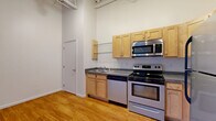 Located at 150 Andrews St in downtown Rochester, NY, this one-bedroom, one-bathroom unit offers an industrial-loft aesthetic with striking architectural character. The open living and dining area is anchored by soaring ceilings with exposed steel trusses and large ductwork, giving the space a distinctive urban feel. Multiple black-framed windows flood the area with natural light and frame views of the surrounding cityscape and greenery. Rich hardwood flooring runs throughout the main living spaces, complementing the bright white walls and enhancing the open, airy ambiance. The kitchen is efficiently designed with light maple cabinetry, dark countertops, glass display shelves, and a full suite of stainless steel appliances including a refrigerator, range, microwave, and dishwasher. The bedroom features plush carpeting and generous wall space, offering a quieter, more intimate retreat. Two closets provide practical storage throughout the unit. The bathroom is finished with clean ceramic tile flooring and includes accessibility-friendly grab bars. The overall design balances industrial character with functional livability, making it a compelling urban residence in the heart of Rochester.