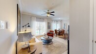 Located in Sugar Land, TX, this single-story 2-bedroom, 2-bathroom home offers a thoughtfully designed layout with modern finishes throughout. The galley-style kitchen is equipped with stainless steel appliances, white shaker cabinetry, and granite countertops, flowing into a peninsula with bar seating and pendant lighting — ideal for casual dining or entertaining. The living room features crown molding, a ceiling fan, wood-look flooring, and a large window that fills the space with natural light. The adjacent dining area continues the bright aesthetic with tall windows dressed in sheer curtains. Both bedrooms are carpeted and comfortable; the primary bedroom includes a vaulted ceiling with a ceiling fan, offering a sense of added openness. Both bathrooms are finished with marble-look tile surrounds, soaking tub-shower combos, granite vanity tops, and white cabinetry with brushed hardware. A hallway connects the rooms efficiently, keeping the layout cohesive. The overall palette is neutral and light throughout, with soft grays and whites creating a clean, modern ambiance well-suited to everyday living.