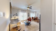 Located in Sugar Land, TX, this single-story 2-bedroom, 2-bathroom home offers a thoughtfully designed layout with modern finishes throughout. The galley-style kitchen is equipped with stainless steel appliances, white shaker cabinetry, and granite countertops, flowing into a peninsula with bar seating and pendant lighting — ideal for casual dining or entertaining. The living room features crown molding, a ceiling fan, wood-look flooring, and a large window that fills the space with natural light. The adjacent dining area continues the bright aesthetic with tall windows dressed in sheer curtains. Both bedrooms are carpeted and comfortable; the primary bedroom includes a vaulted ceiling with a ceiling fan, offering a sense of added openness. Both bathrooms are finished with marble-look tile surrounds, soaking tub-shower combos, granite vanity tops, and white cabinetry with brushed hardware. A hallway connects the rooms efficiently, keeping the layout cohesive. The overall palette is neutral and light throughout, with soft grays and whites creating a clean, modern ambiance well-suited to everyday living.
