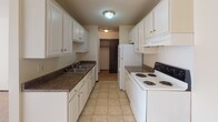 This single-floor unit located in Golden Valley, Minnesota offers a practical and comfortable layout designed for everyday living. The open living area features neutral-toned carpet and a ceiling fan with integrated lighting, creating a bright and airy atmosphere. Natural light streams in through large windows dressed with vertical blinds, casting a warm glow throughout the space. A wall-mounted air conditioning unit and baseboard heating provide year-round climate control.

The galley-style kitchen is efficiently arranged with ample white cabinetry featuring gold hardware, dark laminate countertops, a double-basin sink, and white appliances including an electric range and refrigerator. Tile flooring runs throughout the kitchen, which also provides convenient access to additional storage.

The bedrooms are carpeted and well-lit, each equipped with ceiling fans and large windows that invite natural light. One bedroom features built-in panel cabinetry along an entire wall, offering generous storage.

The bathroom includes a combined tub and shower unit, tile flooring, and grab bars for added accessibility. The overall design is clean, neutral, and functional, offering a comfortable living environment in a convenient Golden Valley location.