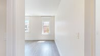 This well-appointed 3-bedroom, 2-bathroom residence in Memphis, TN offers a clean, modern aesthetic throughout its single-floor layout. Light-toned hardwood-style flooring flows consistently across the living areas and bedrooms, creating a cohesive and welcoming atmosphere. Crisp white walls and trim complement the neutral palette, while textured ceilings add a subtle architectural detail to each room.

The living area benefits from multiple large windows with white-trimmed frames that flood the space with natural light and provide views of the surrounding urban streetscape. Each of the three bedrooms continues this bright, airy character, with generous windows framing city views and allowing sunlight to pour across the floors throughout the day.

The galley-style kitchen is efficiently designed, featuring dark cabinetry contrasted against white countertops, a double-basin stainless steel sink, and a full suite of stainless steel appliances including a refrigerator, range, microwave, and dishwasher. Both bathrooms are finished with large-format taupe tile surrounds in the tub-shower combinations, paired with dark vanity cabinetry and clean white fixtures. A dedicated laundry room with an in-unit washer adds everyday convenience. A connecting hallway ties all areas together in a practical and straightforward layout.