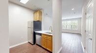 Located at 40 East Hanover Avenue in Morris Plains, NJ, this well-appointed one-bedroom, one-bathroom residence offers a thoughtfully designed single-floor layout. Wood-style flooring flows consistently throughout the entire space, lending warmth and visual continuity to every room.

The kitchen is efficiently arranged with warm-toned wood cabinetry, white countertops, and a full suite of stainless steel appliances including a refrigerator, dishwasher, electric range, and over-the-range microwave. A gold-toned faucet at the sink adds a refined detail, and a skylight above brings in additional natural light. The kitchen opens directly into the combined dining and living area, which is generously proportioned, bathed in natural light from large windows with views of surrounding greenery, and finished with recessed lighting.

The bedroom is a comfortable, well-lit room with a window overlooking the outdoors, neutral walls, and ample space. Two closets provide practical storage. The bathroom features a white vanity with an undermount sink, a framed mirror, and clean, neutral finishes throughout. A dedicated laundry area and a hallway with additional storage complete the functional layout of this efficient and move-in-ready residence.