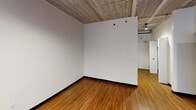 Located at 618 S Main St in Ann Arbor, Michigan, this single-floor unit offers a thoughtfully arranged open layout that maximizes its compact footprint. The space exudes an industrial-modern aesthetic, defined by striking exposed concrete ceilings with visible structural elements and warm hardwood flooring that runs throughout.

The kitchen is a standout feature, equipped with a full suite of stainless steel appliances including a refrigerator, dishwasher, electric range with microwave above, and a stainless steel sink set into dark countertops. Warm-toned wooden cabinetry, including a decorative wine rack detail, provides ample storage. Track lighting overhead and a large sliding glass door with blinds allow natural light to pour in while offering access to an outdoor area.

The open living space connects seamlessly to the kitchen, maintaining the industrial character with its exposed ceiling and neutral white walls. Recessed lighting complements the natural light entering the space.

The bathroom is clean and functional, featuring subway tile walls in the walk-in shower stall with a chrome showerhead, hardwood-style flooring, and safety grab bars. The overall design blends utilitarian elements with modern finishes, making this a practical and characterful space in a prime Ann Arbor location.