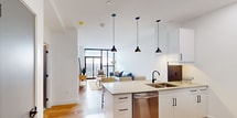This contemporary 490 square foot apartment at 110 Fullarton, 3006, maximizes its compact footprint with a thoughtful layout. The space comprises one bedroom, one bathroom, and an open-concept living area. Floor-to-ceiling windows in the living room and bedroom flood the space with natural light and offer breathtaking city views.

The kitchen boasts sleek, modern appliances, including a stainless steel refrigerator and oven. White cabinetry is complemented by a geometric tile backsplash, while pendant lighting adds a touch of sophistication. A breakfast bar with seating for three separates the kitchen from the living area.

The living room features a comfortable gray sofa, accent chair, and round coffee table, all resting on a natural fiber rug atop hardwood flooring. The bedroom accommodates a queen-size bed and offers ample closet space with sliding doors. 

The bathroom is efficiently designed with a combined tub and shower, featuring a curved shower rod and clean white tiles. A wooden vanity provides storage beneath the sink.

Throughout the apartment, the color palette is primarily neutral, creating a sense of spaciousness. Strategic placement of plants and artwork adds warmth and personality to the space. The apartment also includes modern amenities such as recessed lighting and a wall-mounted air conditioning unit, ensuring comfort in this stylish urban dwelling.