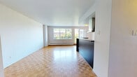 Located at 1100 Avenue du Docteur-Penfield in the heart of Montréal, this 2-bedroom, 2-bathroom unit offers a well-designed layout across a single floor. The open-concept living and dining area is anchored by warm parquet flooring in a classic checkerboard pattern, which flows throughout the entire unit. Large windows invite abundant natural light and frame greenery and city views, creating a bright and welcoming atmosphere.

The kitchen features a sleek, dark-toned peninsula with modern cabinetry and a stainless steel range hood, seamlessly integrating with the living space while providing a clear functional separation. The layout is practical and efficient, with two generously sized closets offering ample storage.

Both bedrooms are well-proportioned and finished with the same warm parquet flooring. One bedroom benefits from a striking view of the Montréal downtown skyline, while the other overlooks lush treetops — both serviced by baseboard heating throughout. The bathroom is clean and functional, featuring light tile flooring, a vanity with mirror cabinet, and a bathtub-shower combination. The unit's clean white walls and consistent finishes throughout give it a cohesive, move-in-ready feel.