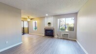 Located at 2130 S Santa Fe Ave in Vista, California, this single-floor residence offers a well-organized layout with thoughtfully updated finishes throughout. The open living area serves as the heart of the home, anchored by a stone-surround fireplace with a classic white mantle and complemented by light wood-style flooring that flows seamlessly through the space. Large windows on multiple walls invite abundant natural light and provide views of the surrounding greenery and neighborhood, while a ceiling fan adds comfort and functionality overhead. A wall-mounted A/C unit ensures year-round climate control.

The kitchen is efficiently laid out in a galley style, featuring gray shaker cabinetry, light granite-style countertops, a stainless steel sink, and a full-size stainless steel refrigerator, with a dishwasher included for added convenience. The kitchen opens toward the main living and dining areas, making the space feel connected and functional.

The bedrooms are comfortably sized with neutral-toned walls, textured ceilings, and light to medium-tone wood-style flooring, each featuring windows that bring in natural daylight. The bathrooms are clean and well-appointed — one includes a soaking tub and shower combination with a chrome fixture, while the other features a shaker-style vanity with a white sink, large mirror, and additional storage cabinetry above.