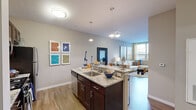 Located at 254 Crown St in New Haven, CT, this one-bedroom, one-bathroom unit offers a thoughtfully designed layout that maximizes its compact footprint. The open-concept kitchen flows seamlessly into the living area, creating a connected and functional living space. The kitchen is outfitted with rich dark-wood cabinetry, granite countertops, stainless steel appliances including a gas range and French door refrigerator, and a peninsula with bar seating illuminated by stylish pendant lighting. Hardwood-style flooring runs throughout the main living areas, adding warmth and continuity. The living room benefits from large windows that invite natural light and offer outdoor views, complemented by neutral-toned walls that provide a versatile backdrop. The bedroom features plush carpeting, generous windows with views, and direct access to a walk-in closet. A conveniently located in-unit stacked washer and dryer adds everyday practicality. The bathroom is finished with white tile, a full soaking tub and shower combination, and bold accent walls. The entrance provides a welcoming transition into the space. Overall, the unit presents a modern, urban aesthetic well-suited for comfortable city living in New Haven.