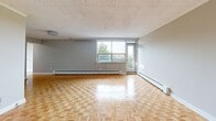Located at 276 Saint Clair Avenue West in Toronto's desirable midtown neighbourhood, this two-bedroom, one-bathroom unit offers a practical and comfortable layout across a single floor. The generously sized primary bedroom is notably spacious, providing ample room for furnishings and storage, complete with dual sliding-door closets. The second bedroom benefits from a large window framing lush treetop and park views, filling the room with natural light. Warm parquet flooring runs throughout the living areas and bedrooms, adding classic character to the neutral grey-toned walls. The living area is expansive and bright, featuring baseboard heating and windows that overlook the surrounding green parkland. The galley-style kitchen is fitted with clean white cabinetry, marble-style countertops, a stainless steel sink, and tile flooring, with an open passage connecting it to the rest of the unit. The full bathroom is finished in crisp white with large-format floor tiles, a soaker tub with overhead shower, vanity with storage, and a mirror. A hallway provides a welcoming entry point. The outlook from this fourth-floor unit captures open park greenery and mature trees, offering a tranquil urban setting on Saint Clair West.