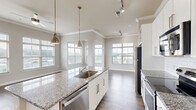 Located at 306 Ardmore Cir NW in Atlanta, GA, this well-appointed 2-bedroom, 2-bathroom residence offers a thoughtfully designed single-level layout with generous living space. The open-concept kitchen and living area serves as the heart of the home, featuring a large granite-topped island with pendant lighting, white shaker cabinetry, a white subway tile backsplash, stainless steel appliances, and wood-style flooring that flows throughout the main areas. Crown molding and track lighting add refined detail to the kitchen-living space. The living and dining areas are bathed in natural light from multiple large windows fitted with horizontal blinds, offering views of the surrounding neighborhood and cityscape. Both bedrooms are carpeted and feature ceiling fans and bright windows. The spacious primary bedroom includes a generous walk-in closet with built-in wire shelving. The two bathrooms mirror each other in finish quality, each showcasing granite-topped vanities with white cabinetry, wood-style tile flooring, and a tiled tub-shower combination. A dedicated hallway connects the private quarters to the main living areas, completing a functional and cohesive floor plan ideal for comfortable everyday living.