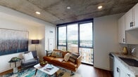 Located at 1720 Oak Ave in Evanston, Illinois, this contemporary residence showcases an industrial-modern aesthetic defined by striking exposed concrete ceilings throughout. The open-concept living area is anchored by expansive floor-to-ceiling windows framed in dark metal, flooding the space with natural light and offering sweeping elevated views of the Evanston skyline and surrounding treetops. Rich hardwood flooring runs throughout, providing a warm contrast to the raw concrete overhead.

The kitchen is outfitted with white shaker cabinetry, granite countertops, a classic subway tile backsplash, and a full suite of stainless steel appliances, including a gas range, built-in microwave, dishwasher, and French door refrigerator — combining both style and functionality.

The bedroom continues the exposed concrete aesthetic, creating a cohesive industrial feel, while remaining a calm and comfortable retreat. The bathroom features a glass-enclosed walk-in shower with large-format neutral tile, a built-in marble bench, and chrome grab bars, reflecting a clean and refined finish.

The overall ambiance of this residence is one of sophisticated urban living — blending raw architectural elements with modern finishes to create a space that is both visually dynamic and highly livable.
