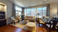This single-floor residence at 100–108 University Ave in Westwood, Massachusetts offers a well-appointed, open-concept layout with contemporary finishes throughout. The living and dining area serves as the centerpiece of the space, distinguished by expansive floor-to-ceiling windows that flood the room with natural light and provide sweeping outdoor views. Rich hardwood flooring runs throughout the main living areas, complementing the warm, neutral color palette.

The kitchen is designed for both functionality and style, featuring dark espresso cabinetry, granite countertops, a mosaic tile backsplash, and a full suite of stainless steel appliances, including a side-by-side refrigerator, electric range, built-in microwave, and dishwasher. A window above the counter adds additional natural light to the workspace.

The bedroom is a comfortable retreat with plush carpeting, a ceiling fan, and a window with outdoor views. It is paired with a well-organized walk-in closet and a private bathroom finished in light tile, dark cabinetry, and a generous vanity. A second bathroom mirrors similar design elements, maintaining a cohesive aesthetic throughout.

Overall, the space combines modern urban design with thoughtful finishes, creating a polished and functional living environment.
