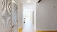 Located in San Diego's vibrant urban core, this well-appointed 1-bedroom, 2-bathroom residence offers a thoughtfully designed layout with contemporary finishes throughout. Elegant herringbone-patterned hardwood flooring flows continuously across the entire unit, lending warmth and visual interest to every room.

The open-concept kitchen and living area serves as the heart of the home. The kitchen is outfitted with stainless steel appliances, including a gas range, microwave, refrigerator, and dishwasher, complemented by crisp white shaker cabinetry, a white subway tile backsplash, and dark stone countertops. A peninsula with a flexible overhang connects the kitchen to the living area, while three striking black-and-gold pendant lights add a bold design accent overhead.

Floor-to-ceiling windows and a glass-panel door in the living area flood the space with natural light and open to a private balcony overlooking sweeping San Diego cityscape views. The generously sized primary bedroom also benefits from expansive window coverage and direct outdoor access, along with a dedicated walk-in closet.

Both bathrooms are finished with large-format marble-look tile on the floors and walls, paired with white vanities and clean, modern fixtures. A hallway with louvered closet doors provides additional storage. The overall aesthetic is bright, clean, and modern — an ideal urban retreat.