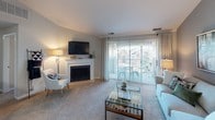 This single-floor residence offers a thoughtfully designed layout with distinct living spaces that balance comfort and functionality. The living room serves as the heart of the home, highlighted by a fireplace framed with a white mantel, plush carpeting, and sliding glass doors that open to a private balcony overlooking the surrounding neighborhood. Natural light filters through sheer curtains, creating a bright and welcoming atmosphere.

Adjacent to the living room, the dining area features a ceiling fan and neutral walls, providing a relaxed setting for everyday meals. The kitchen is well-equipped with stainless steel appliances—including a range, microwave, and refrigerator—complemented by dark countertops, white cabinetry, and a classic subway tile backsplash. Wood-style flooring adds warmth underfoot.

The bedrooms are carpeted and serene, with windows admitting ample natural light. The primary bedroom connects to a hallway leading to a walk-in closet and a vanity area featuring a long dark-granite countertop with white cabinetry and a wide mirror. A secondary bathroom includes a shower-tub combo and hardwood-style flooring, completing this comfortable and cohesive residence.