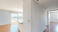 Located at 165 N Hoover St in Los Angeles, this 3-bedroom, 2-bathroom unit offers a well-designed single-floor layout that maximizes every inch of its compact footprint. Rich hardwood flooring flows throughout the living areas, bedrooms, and hallway, lending warmth and continuity to the space.

The open-concept kitchen and living area serves as the heart of the unit. The kitchen is outfitted with white cabinetry, granite countertops, a mosaic tile backsplash in blue and grey tones, and stainless steel appliances including a gas range and dishwasher. A peninsula counter with a granite top provides additional prep space and separates the kitchen from the living area. Track lighting overhead and a sliding glass door leading to the balcony fill the space with natural light, while the balcony offers striking views of the Los Angeles skyline.

The three bedrooms are bright and well-proportioned, with light-toned walls and large windows that frame city and treetop views. The primary bedroom is comfortably sized with ample natural light. A hallway connects the bedrooms to both bathrooms, which feature marble-style tile surrounds on the tub and shower areas, granite vanity countertops, and clean white cabinetry.