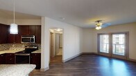 This single-story unit at 404 S Mary St in Arlington, Texas, offers a thoughtfully designed layout that balances functionality and style. The open-concept living and kitchen area serves as the heart of the space, where dark hardwood-style flooring extends throughout, complemented by crisp white walls and classic ceiling light fixtures. A window in the living area allows natural light to filter in, enhancing the overall brightness of the space.

The kitchen is well-appointed with rich dark cabinetry, granite countertops, a mosaic tile backsplash, and a full suite of stainless steel appliances, including a refrigerator, microwave, and range. Track lighting overhead provides targeted illumination, while a pantry closet adds convenient storage. The kitchen flows naturally into the living area via a partial wall, maintaining an open, connected feel.

The bedroom features soft wall-to-wall carpeting, a ceiling light fixture, and a window with blinds that allows natural light in. An additional room with hardwood-style flooring offers flexible use as a secondary bedroom or office space. The bathroom includes a soaking tub with a tiled surround, brushed nickel fixtures, and granite countertop detailing, providing a clean and functional finish throughout.