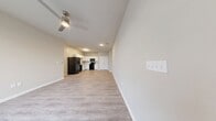 This 780 square foot, two-bedroom, one-bathroom apartment at 1300 N Lancaster Rd in South Elgin, IL offers a practical and modern single-floor layout. The open-concept kitchen and living area is anchored by light wood-look vinyl plank flooring throughout, with a ceiling fan in the living room and natural light streaming through large windows with blinds. The kitchen features white cabinetry with light countertops, a full suite of black appliances including a refrigerator, range, built-in microwave, and dishwasher, as well as a stainless steel sink. Both bedrooms are carpeted; the primary bedroom measures 150 square feet and the secondary bedroom includes a double-door closet. The primary bedroom is served by a spacious walk-in closet with wire shelving on multiple walls. The full bathroom is finished with wood-look vinyl flooring, a white vanity, and a tub/shower combo. A dedicated laundry room houses a full-size GE top-load washer and dryer with wire shelving above. Neutral, warm-toned walls throughout give the unit a clean and cohesive feel.