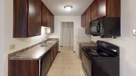 Located at 3359 Coachman Road in Eagan, Minnesota, this single-floor unit offers a straightforward, functional layout designed for comfortable everyday living. The galley-style kitchen is a standout feature, lined on both sides with rich dark-wood cabinetry that provides generous storage. Black appliances, including an electric range, microwave, and refrigerator, complement the dark cabinetry, while laminate countertops and tile flooring complete the kitchen's practical design. A peninsula counter separates the kitchen from the adjoining hallway, which leads to the rest of the unit.

The living area is generously sized and finished with wall-to-wall carpeting, neutral walls, and a ceiling fan. A large sliding glass door fitted with vertical blinds allows natural light to fill the room and provides an outdoor view. The bedroom areas are also carpeted and naturally lit through windows with vertical blinds. One bedroom features a spacious walk-in closet equipped with dual hanging rods and built-in shelving on both sides, offering ample storage capacity.

The full bathroom includes a single-sink vanity with dark wood cabinetry, a toilet, and a full-size soaking tub with an overhead shower. Tile flooring and a textured ceiling are consistent throughout the wet areas of the unit.