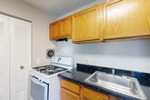 Located at 6500 Ronald Rd in Capitol Heights, MD, this one-bedroom, one-bathroom residence offers a well-organized single-floor layout designed for comfortable everyday living. The living area is bright and open, featuring plush carpeting, neutral gray walls, and large sliding glass doors that flood the space with natural light and open directly onto a private balcony. The balcony overlooks a landscaped lawn with mature trees, providing a peaceful outdoor retreat with pleasant views of the surrounding community. The kitchen is equipped with a gas range, warm wood-toned cabinetry, and easy-to-maintain tile-style flooring. A louvered bi-fold closet door provides convenient pantry or utility storage, and a windowed partition adds a touch of character to the space. The bedroom is a comfortable, carpeted room with a large window that brings in natural light and offers views of the greenery outside. It connects to a spacious walk-in closet outfitted with built-in shelving on multiple walls, offering ample storage capacity. The bathroom features a full-sized soaking tub with tiled surround, a vanity with a white countertop, and tile flooring. Clean, neutral finishes throughout the unit create a cohesive and move-in-ready atmosphere.