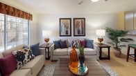 This single-floor residence offers a thoughtfully arranged layout that balances comfort and functionality across its key living areas. The living room serves as the heart of the home, featuring a ceiling fan, soft carpeted flooring, and a large window that invites natural light. Neutral-toned sofas, decorative accent pillows, and curated wall art create a warm and inviting atmosphere ideal for relaxing or entertaining.

Adjacent to the living area, a compact dining nook provides an intimate setting for meals, complete with wood-look flooring, a round dining table, and a tasteful gallery wall arrangement. The kitchen is efficiently designed with ample cabinetry in a light wood finish, a double-basin sink, and full appliances including a range, microwave, refrigerator, and dishwasher, all set on easy-care wood-look flooring.

The bedroom is a serene retreat, offering plush carpeted floors, a spacious closet, and soft ambient lighting from bedside lamps. Decorative artwork adds a personal touch to the calm, neutral walls.

The bathroom is clean and bright, featuring wood-look flooring, a single-sink vanity with storage, and a full shower-tub combination. Overall, the residence presents a cohesive, comfortable living environment with practical finishes and a welcoming aesthetic throughout.