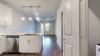 This well-appointed 600-square-foot, one-bedroom, one-bathroom apartment is designed with a modern, functional layout spread across a single floor. The open-concept kitchen serves as the centerpiece of the unit, featuring sleek white cabinetry, stainless steel appliances including a refrigerator, range, and microwave, a mosaic tile backsplash, and a large kitchen island with light granite countertops illuminated by three globe pendant lights — ideal for both cooking and casual dining. Hardwood-style flooring flows consistently throughout the entire unit, lending a cohesive and contemporary feel. The 150-square-foot primary bedroom offers a ceiling fan, a large window with blinds that invites natural light and outdoor views, and direct access to both the bathroom and the closet. The bathroom is clean and functional, showcasing white cabinetry, a granite vanity with a large mirror, and a full soaking tub with a tiled surround. A dedicated closet provides convenient storage. Neutral gray-toned walls throughout the apartment create a calm, versatile backdrop, and ceiling fans in the main living areas add comfort. The thoughtful design maximizes every inch of this compact yet complete living space.