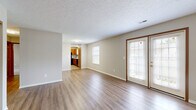 Located at 4133 Parkview Lake Dr. in Columbus, Ohio, this single-floor, 3-bedroom, 2-bathroom home offers a comfortable and functional layout. The combined living and dining area serves as the heart of the home, featuring warm hardwood-style flooring, a textured ceiling, and a corner fireplace with a classic white surround. French doors with wood-framed accents flood the space with natural light and provide direct access to the outdoor patio, seamlessly connecting indoor and outdoor living. The kitchen is well-appointed with warm honey-toned cabinetry, light granite-style countertops, black appliances including a range, microwave, refrigerator, and dishwasher, and a double stainless steel sink beneath a natural light-admitting window. The three bedrooms offer plush carpeting, neutral tones, and generous closet space, including sliding-door wardrobes. The spacious primary bedroom provides a comfortable retreat with ample room. Both bathrooms feature stone-tile flooring, wood-toned vanities with granite-style counters, and clean white fixtures — one with a tub/shower combo, the other with a walk-in shower. Additional highlights include a dedicated laundry room, utility room, hallway, and five closets providing exceptional storage throughout.