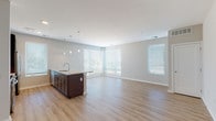 This single-floor unit showcases a clean, contemporary design with a neutral color palette and light hardwood-style flooring that runs consistently throughout the space. The open-concept layout connects the kitchen and living area seamlessly, creating a generous, airy atmosphere enhanced by multiple windows fitted with horizontal blinds that allow abundant natural light.

The kitchen is a standout feature, equipped with stainless steel appliances including a French door refrigerator, range, and microwave. Gray shaker-style cabinetry pairs with light granite countertops and a subtle subway tile backsplash. A central island with dark cabinetry, a built-in sink, and pendant lighting above serves as both a functional workspace and a visual anchor for the open living area.

The bedrooms are well-proportioned, each featuring the same hardwood-style flooring, neutral walls, and windows that bring in natural light. The unit includes two bathrooms: a full bath with a soaking tub, white tile surround, and chrome fixtures, and a second bathroom featuring a walk-in glass-enclosed shower, a dark-cabinetry vanity with granite countertop, and large-format tile flooring. Overall, the unit offers a bright, functional, and cohesive living environment.
