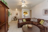 This single-floor residence offers a comfortable and functional layout across several well-defined living spaces. The living room serves as the heart of the home, featuring a built-in fireplace topped with a wall-mounted television, plush carpeted flooring, and a glass door that opens to the outside, filling the room with natural light. Adjacent to the living room is a casual dining area with enough space for a bistro-style table and chairs, accented by decorative wall art and connected directly to the kitchen. The galley-style kitchen is efficiently designed with warm wood cabinetry, white appliances including a stove, refrigerator, dishwasher, and microwave, complemented by light tile flooring and ample counter space. The primary bedroom is generously sized, featuring large windows for natural light, carpet flooring, and access to a walk-in closet. A second bedroom offers a bright and versatile space, also with carpeted floors and a sizable window. The bathroom is clean and functional, outfitted with a tub-shower combo featuring sliding glass doors and tile flooring. Throughout, neutral tones and soft carpeting create a warm, inviting ambiance suited for comfortable everyday living.