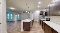 Located at 9940 Mahaffey Dr in Palmetto, FL, this single-story, one-bedroom, one-bathroom home offers a thoughtfully designed layout with modern finishes throughout. Wood-look plank flooring flows consistently across the entire living space, creating a cohesive and low-maintenance aesthetic.

The open-concept kitchen and living area serves as the heart of the home. The kitchen is outfitted with rich, dark espresso cabinetry extending to the upper walls, white quartz countertops, and a full suite of stainless steel appliances including a refrigerator, electric range, and over-the-range microwave. A large central island with an integrated sink and pendant lighting above provides additional prep space and serves as a natural gathering point.

The living room is bright and airy, benefiting from multiple windows that invite ample natural light and views of the surrounding outdoors. A ceiling fan adds comfort to the space. The bedroom is generously sized, featuring its own ceiling fan, a window with outdoor views, and neutral tones throughout.

The bathroom features white shaker-style cabinetry, a white quartz vanity top, a large mirror, and brushed nickel fixtures. A dedicated laundry room houses a full-size Whirlpool top-load washer and dryer, complete with overhead wire shelving for added storage.