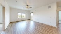 Located in Gilbert, Arizona, this single-story, 3-bedroom, 2-bathroom home offers a well-designed layout with a bright, modern aesthetic throughout. The open-concept kitchen and living area serves as the heart of the home, featuring a central island with a stainless steel sink, light quartz countertops, taupe shaker-style cabinetry, a subway tile backsplash, and a full suite of stainless steel appliances including a refrigerator, range, and over-the-range microwave. Light wood-style flooring flows through the main living areas, complemented by recessed lighting and ceiling fans that enhance the airy feel. The living room is generously sized with a ceiling fan, natural light from large windows with outdoor views, and access to an exterior door. The spacious primary bedroom features wood-style flooring, a ceiling fan, and closet access. The additional bedrooms are finished with plush carpeting and ceiling fans. Both bathrooms are finished in a clean, white palette with wood-style flooring, gray vanities with dark hardware, white countertops, and tub-shower combinations. A dedicated den provides flexible space for a home office or additional living area. Two closets offer ample storage throughout.