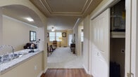 This single-floor residence offers a thoughtfully designed layout that balances comfort and style throughout. The entryway greets visitors with rich hardwood-style flooring and a striking tray ceiling with detailed crown molding, framed by a decorative archway that leads into the main living areas. The living room is generously proportioned, featuring plush carpeting, crown molding, a ceiling fan, and multiple windows that allow ample natural light to fill the space with a warm, inviting ambiance. The kitchen is a standout area, equipped with dark espresso cabinetry, granite countertops, stainless steel appliances, and a peninsula with a double sink that opens through an arched pass-through, maintaining a connected feel with the adjacent spaces. Hardwood-style flooring continues throughout the kitchen and entry areas, adding warmth and visual continuity. The bedroom is a comfortable retreat, carpeted and well-lit by windows with blinds, and is served by a dedicated bathroom featuring dark wood vanity cabinetry, granite countertops, and hardwood-style flooring. A walk-in closet adds practical storage. Throughout the residence, neutral wall tones, consistent trim work, and ceiling fans contribute to a cohesive and comfortable living environment.